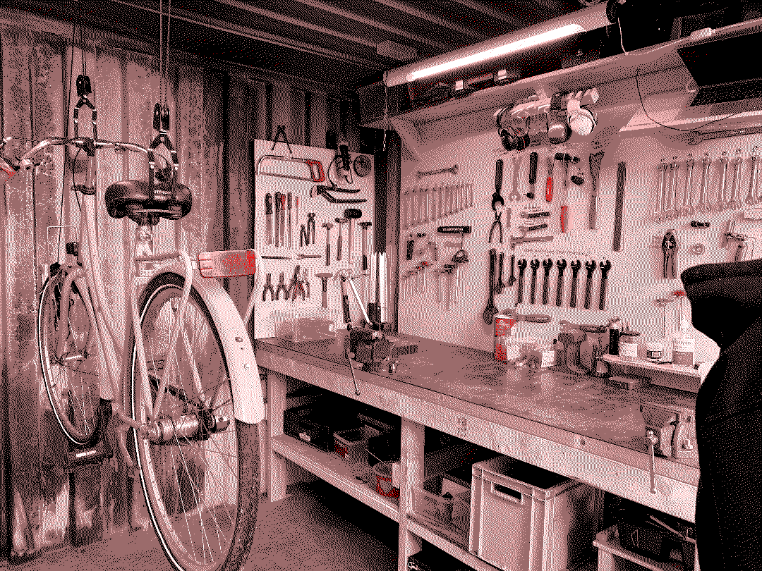 Image of the interior of the bike workshop. A bike hangs on the left and a workbench and to:w
ols are on the right